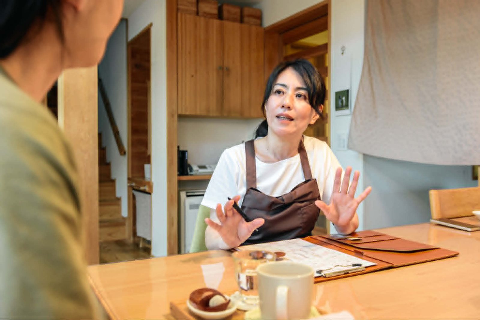 テーブル越しに、身ぶりを交えてお話をうかがう吉田ユウコさん
