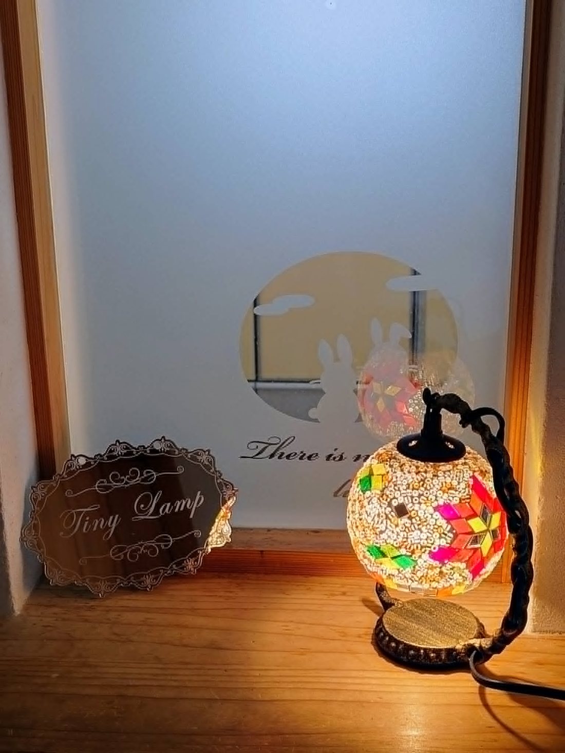 玄関の障子の前に置かれた Tiny Lamp の看板と、モザイクガラスの小さなランプ